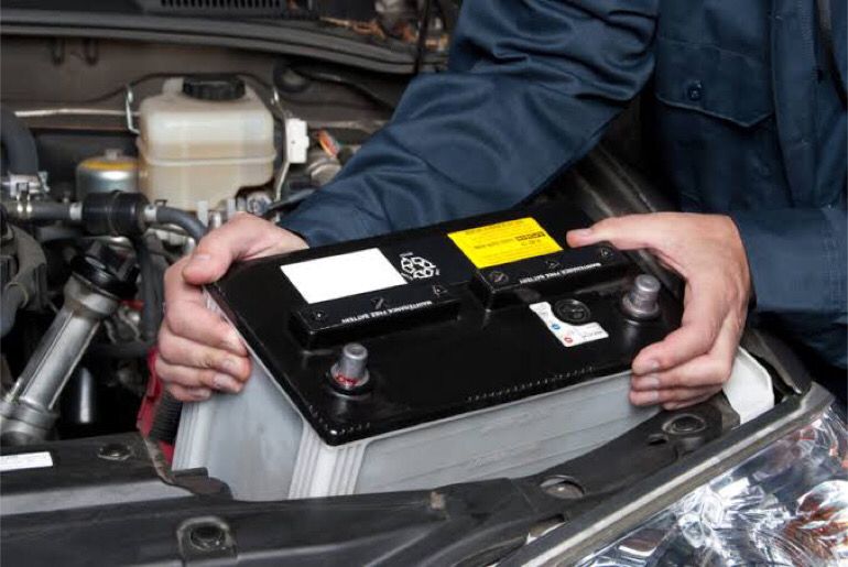 An image showing a man holding a car battery.
