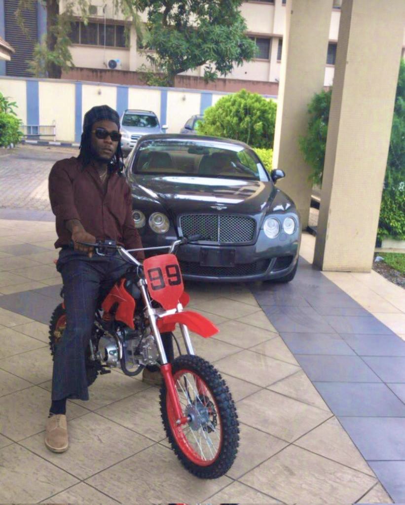 Burna Boy posing with his dirt bike and his Bentley Continental GT